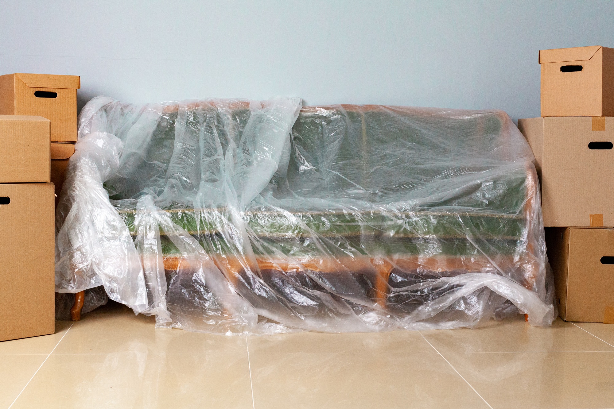 Packed household stuff in boxes and packed sofa for moving