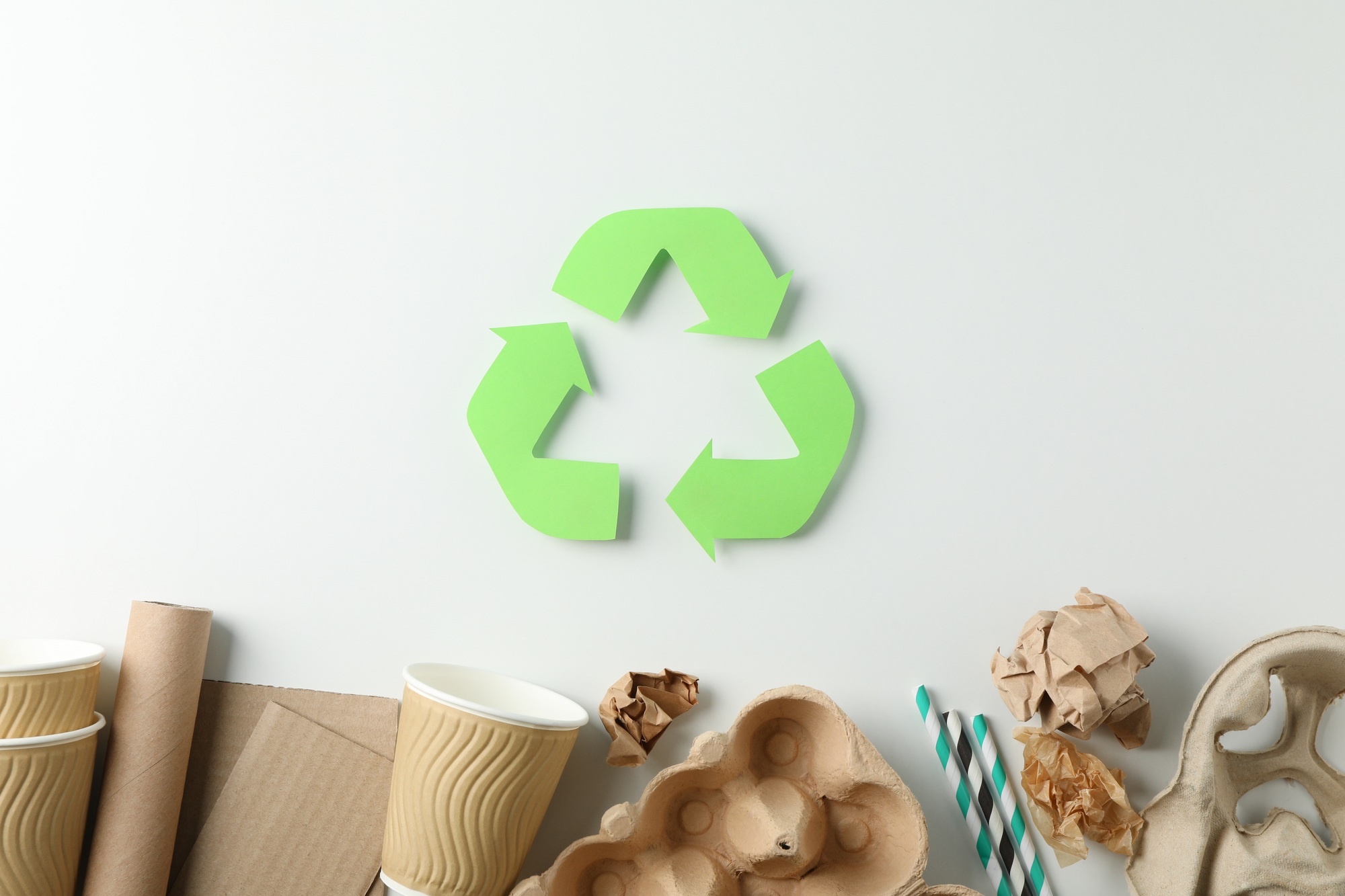 Recycle sign on white background with different trash, top view